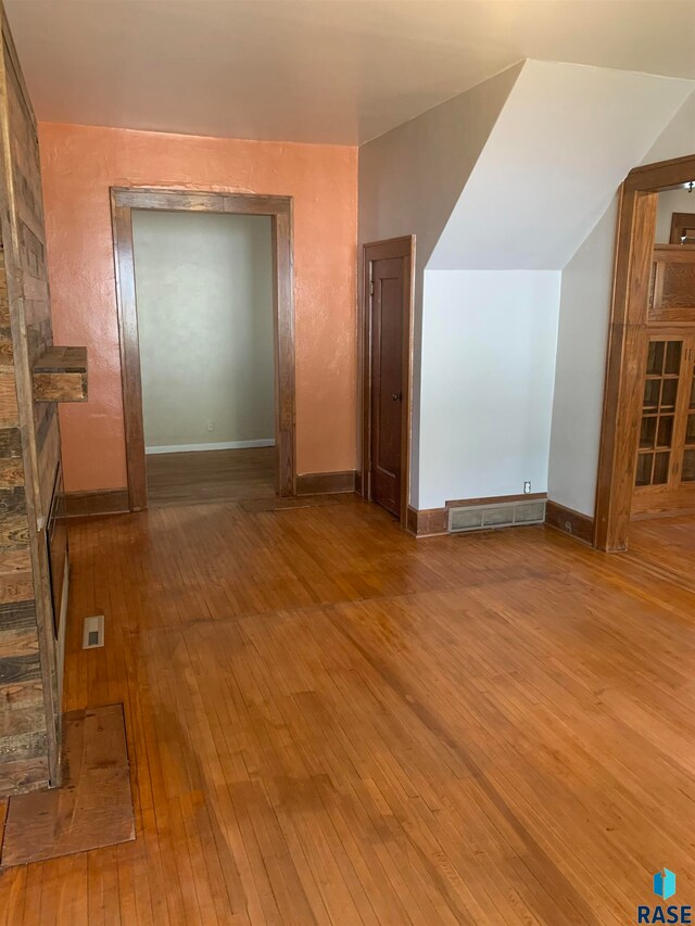 additional living space with vaulted ceiling and hardwood / wood-style flooring