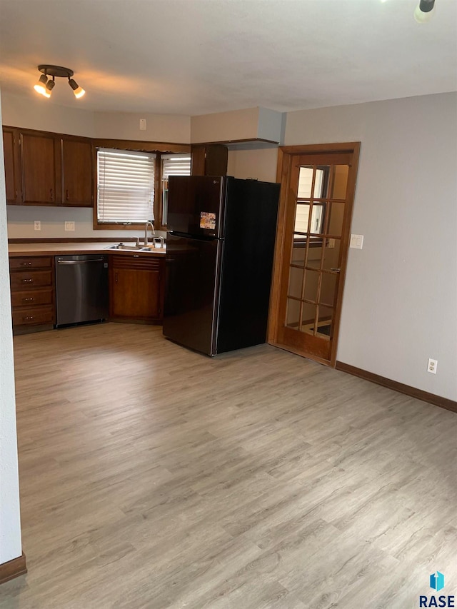 kitchen with sink, light wood-type flooring, black refrigerator, and stainless steel dishwasher