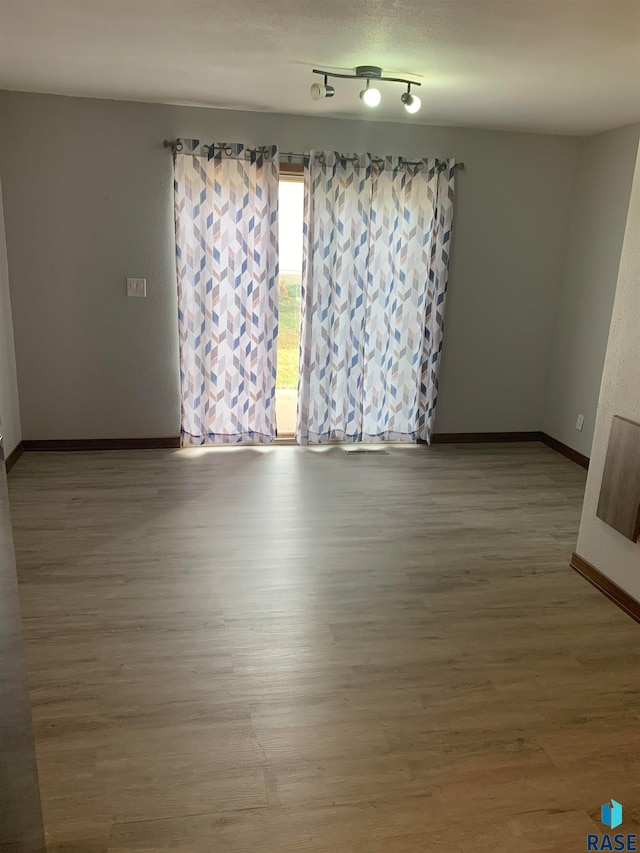 empty room with wood-type flooring and rail lighting