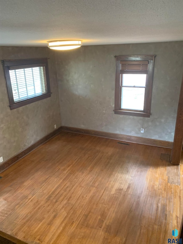 unfurnished room featuring a textured ceiling and hardwood / wood-style flooring