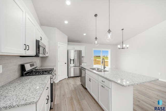 kitchen with an island with sink, sink, decorative light fixtures, white cabinetry, and stainless steel appliances