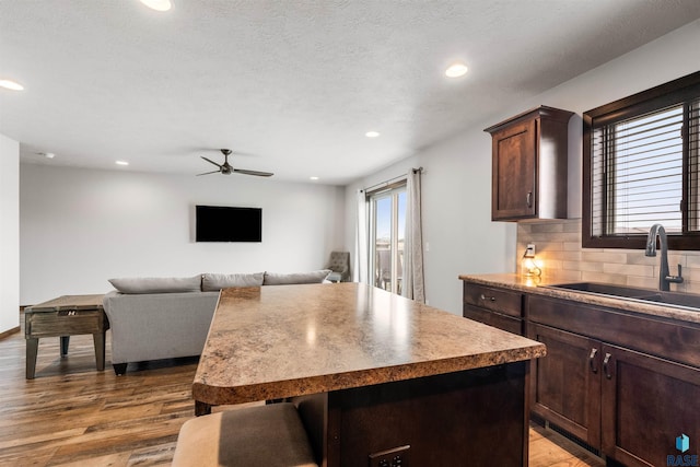 kitchen featuring tasteful backsplash, a kitchen island, light hardwood / wood-style flooring, dark brown cabinets, and sink