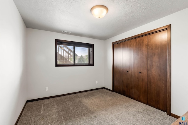 unfurnished bedroom with a closet, carpet flooring, and a textured ceiling