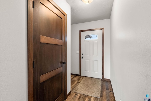 doorway with dark hardwood / wood-style flooring and a textured ceiling