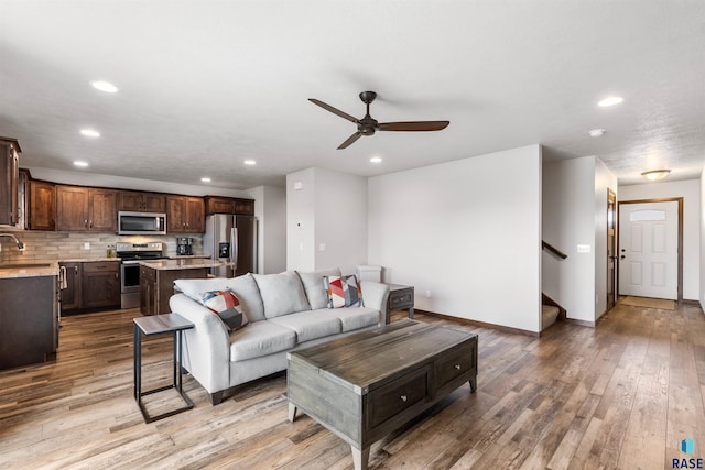 living room with ceiling fan, light hardwood / wood-style flooring, and sink