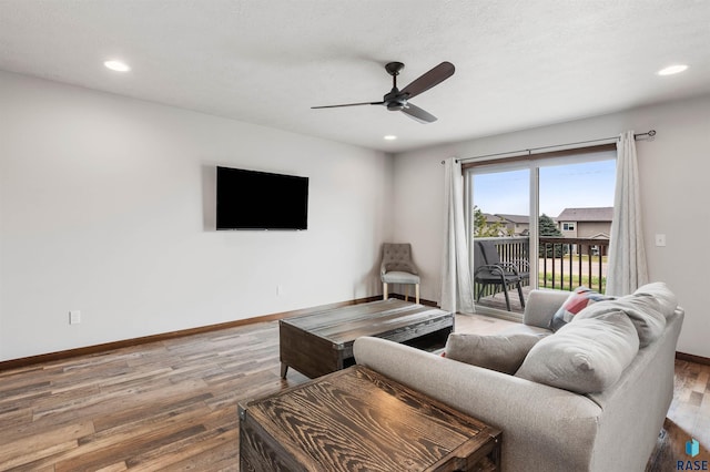 living room featuring ceiling fan, hardwood / wood-style flooring, and a textured ceiling