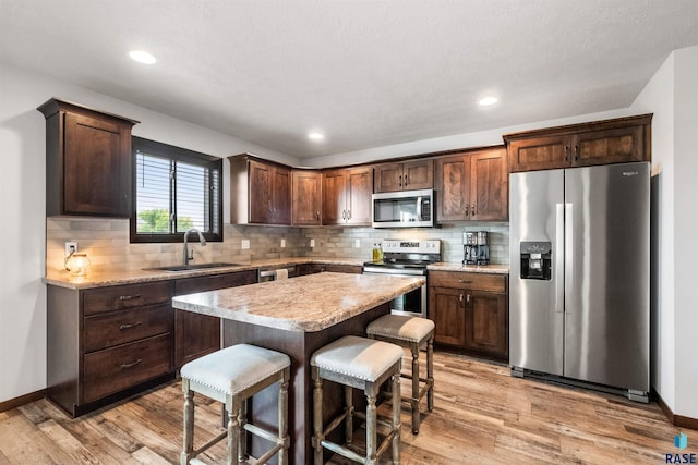 kitchen with light hardwood / wood-style flooring, appliances with stainless steel finishes, sink, and a kitchen island