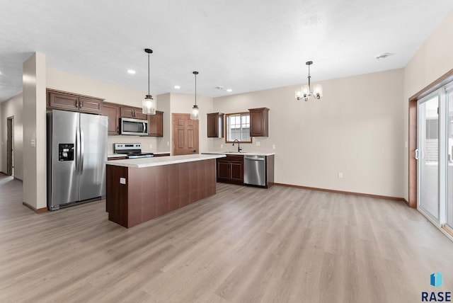 kitchen featuring pendant lighting, a kitchen island, stainless steel appliances, and a healthy amount of sunlight