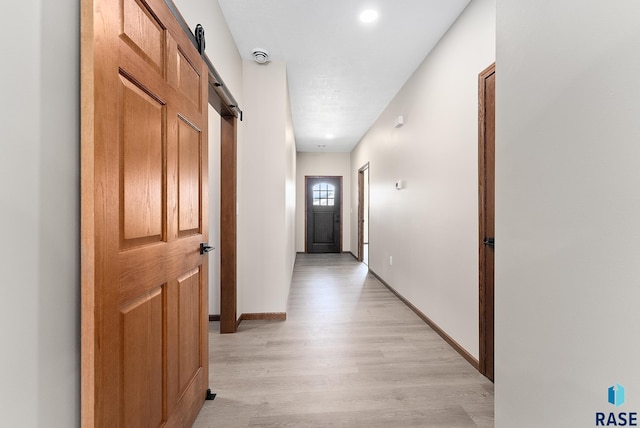 corridor with light hardwood / wood-style flooring and a barn door