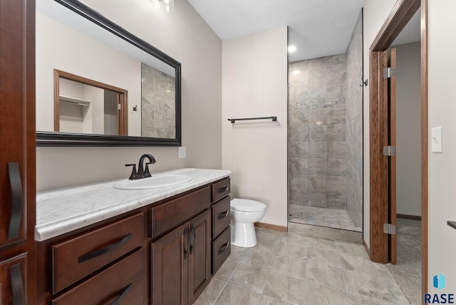 bathroom with vanity, toilet, and tiled shower