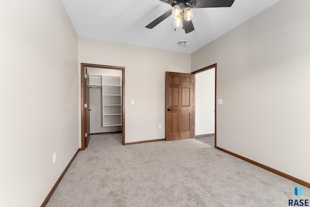 unfurnished bedroom with ceiling fan, a closet, light carpet, and a walk in closet