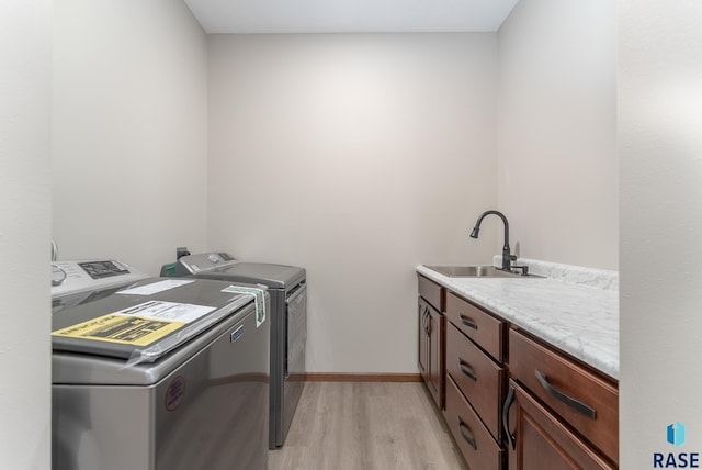 laundry area featuring light hardwood / wood-style flooring, cabinets, washer and clothes dryer, and sink