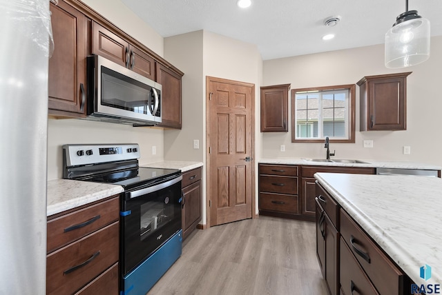 kitchen with pendant lighting, sink, light hardwood / wood-style flooring, appliances with stainless steel finishes, and dark brown cabinetry