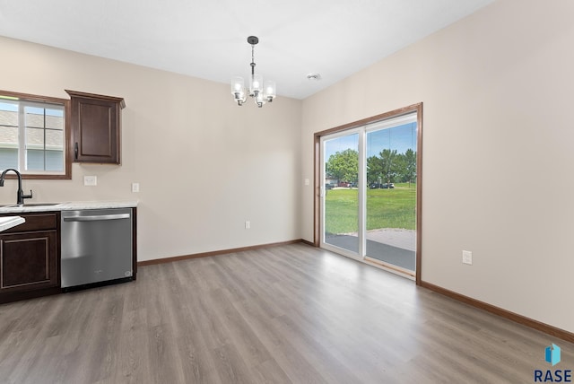 kitchen with dark brown cabinetry, sink, stainless steel dishwasher, decorative light fixtures, and light hardwood / wood-style flooring