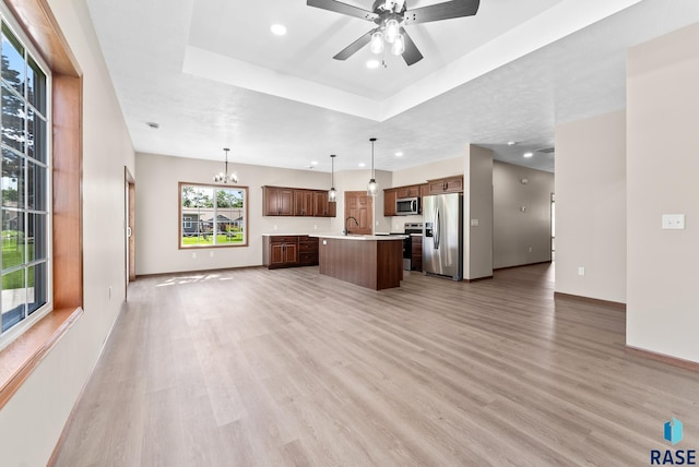 unfurnished living room with wood-type flooring, ceiling fan with notable chandelier, a raised ceiling, and sink