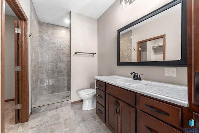 bathroom featuring a tile shower, vanity, and toilet