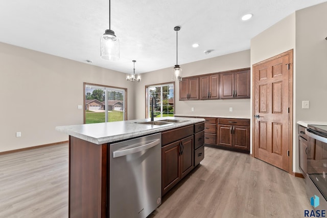 kitchen with appliances with stainless steel finishes, pendant lighting, light wood-type flooring, a center island with sink, and sink