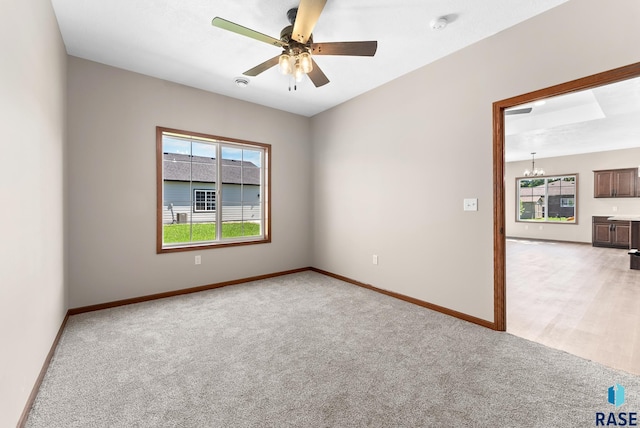 carpeted empty room featuring ceiling fan with notable chandelier