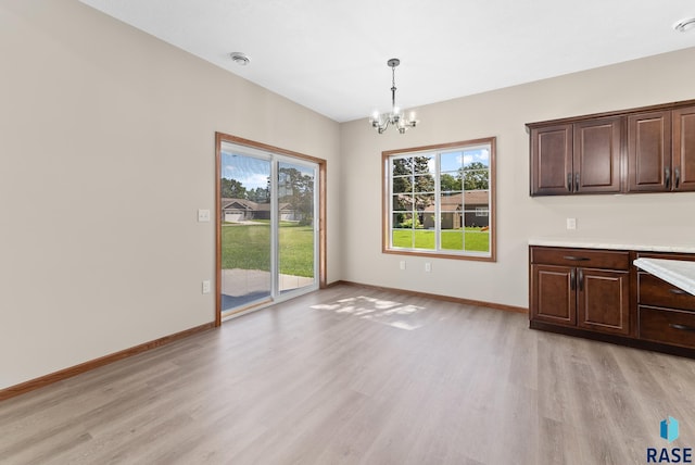 unfurnished dining area with light hardwood / wood-style flooring and a chandelier