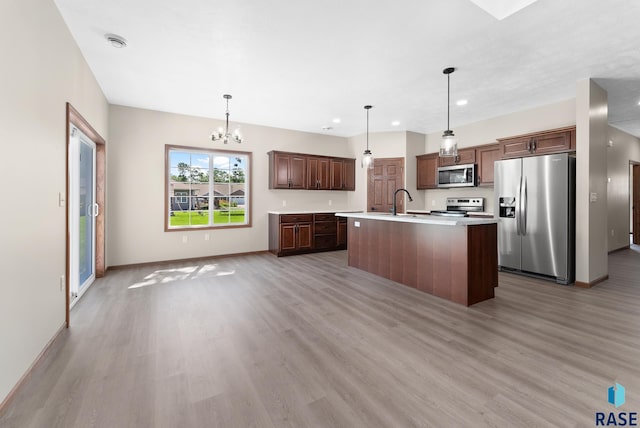 kitchen featuring a kitchen island with sink, pendant lighting, light hardwood / wood-style flooring, and stainless steel appliances