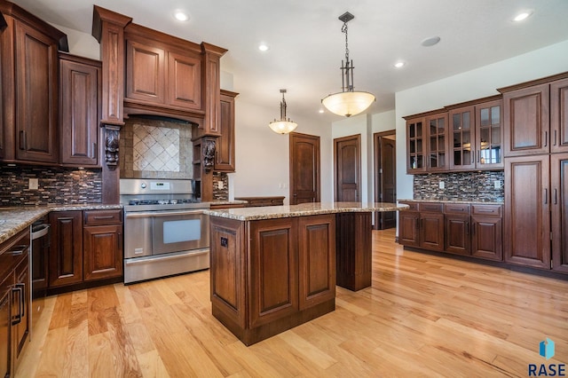 kitchen with pendant lighting, tasteful backsplash, a kitchen island, stainless steel appliances, and light wood-type flooring