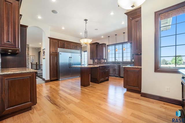 kitchen with decorative light fixtures, appliances with stainless steel finishes, plenty of natural light, and a kitchen island