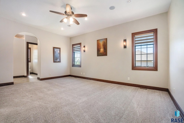 spare room featuring ceiling fan, light colored carpet, and a wealth of natural light