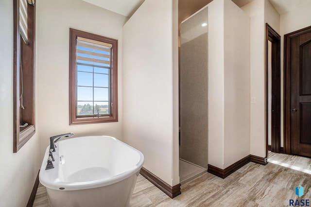 bathroom with a tub to relax in and hardwood / wood-style flooring