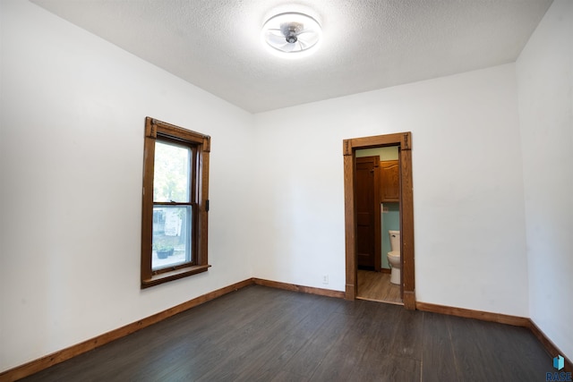 unfurnished room with a textured ceiling and dark wood-type flooring