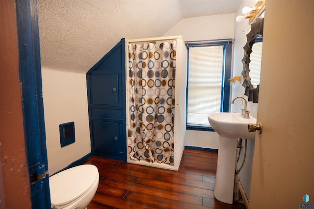 bathroom with wood-type flooring, vaulted ceiling, a textured ceiling, a shower with curtain, and toilet