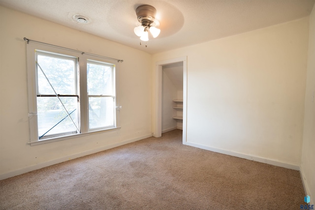 carpeted spare room with ceiling fan and a textured ceiling