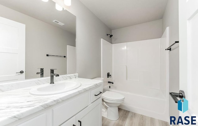 full bathroom featuring washtub / shower combination, vanity, hardwood / wood-style flooring, and toilet