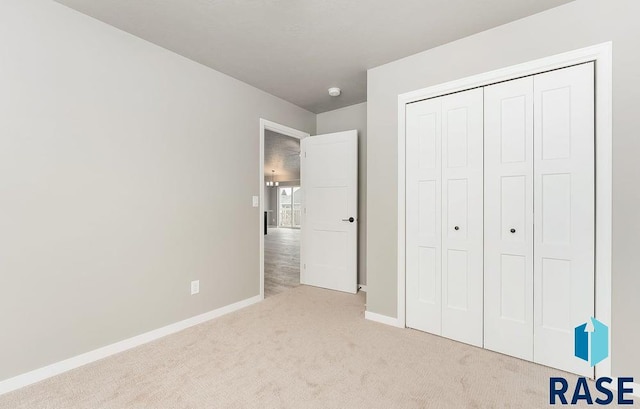 unfurnished bedroom featuring a closet and light colored carpet