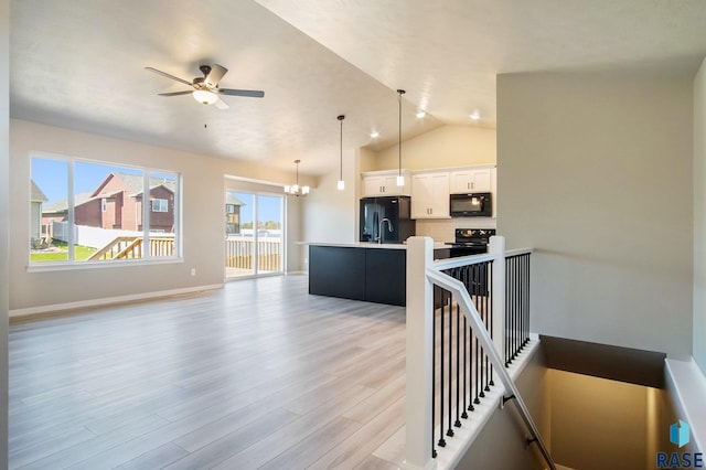 interior space featuring light hardwood / wood-style flooring, ceiling fan with notable chandelier, and lofted ceiling