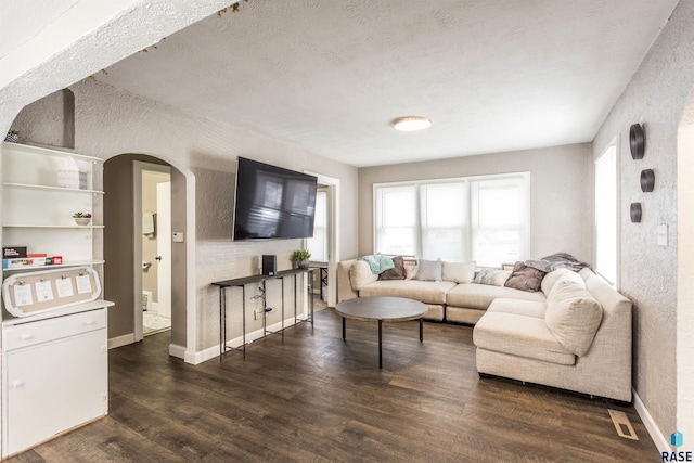 living room with a textured ceiling and dark hardwood / wood-style flooring