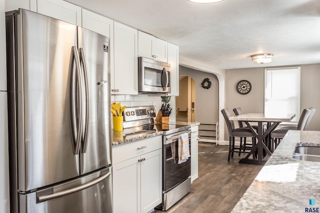 kitchen featuring light stone countertops, stainless steel appliances, dark hardwood / wood-style floors, and white cabinetry