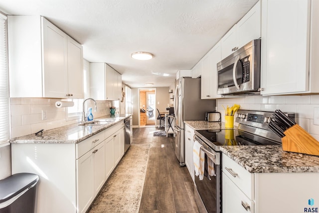 kitchen with appliances with stainless steel finishes, white cabinetry, and dark wood-type flooring