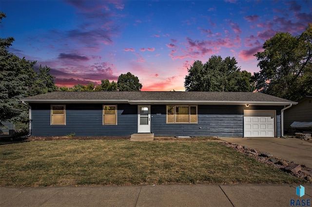 single story home featuring a garage and a lawn