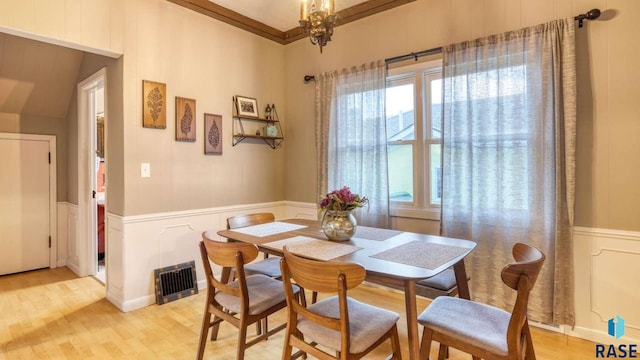 dining space featuring a chandelier, light hardwood / wood-style floors, and crown molding