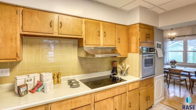 kitchen featuring tasteful backsplash, electric cooktop, light wood-type flooring, oven, and a notable chandelier