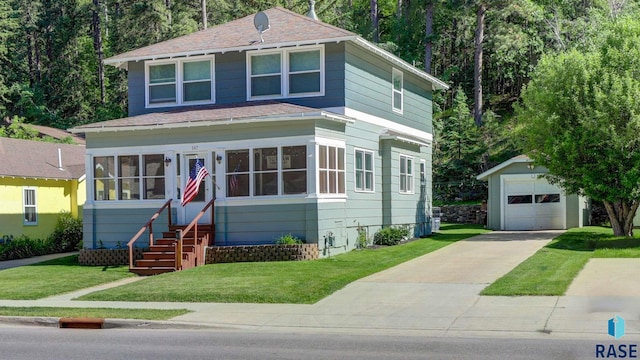 view of front facade featuring a sunroom, a front yard, an outdoor structure, and a garage