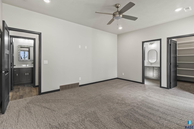 unfurnished bedroom featuring a walk in closet, connected bathroom, visible vents, and carpet