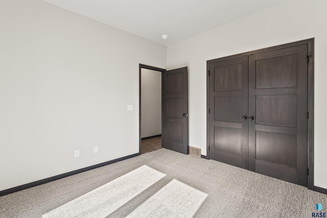 unfurnished bedroom with baseboards, visible vents, carpet floors, and a closet