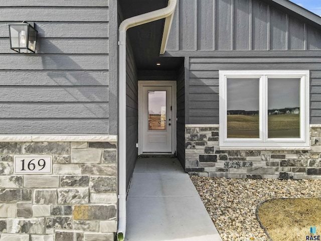 doorway to property with board and batten siding and stone siding