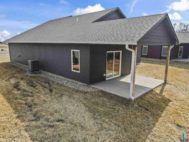 rear view of property with central air condition unit, a patio area, and a shingled roof
