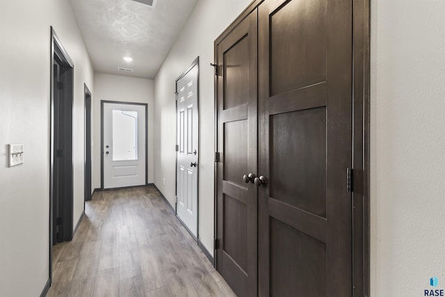 hallway featuring light wood-style flooring and baseboards