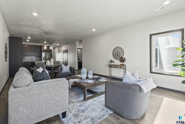 living room with baseboards, wood finished floors, visible vents, and recessed lighting