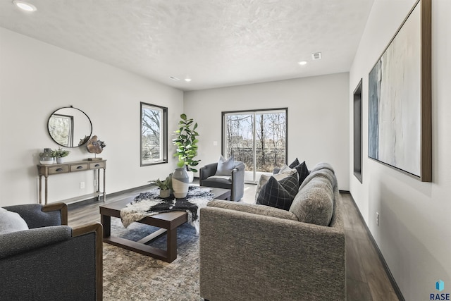 living area with recessed lighting, wood finished floors, a textured ceiling, and baseboards