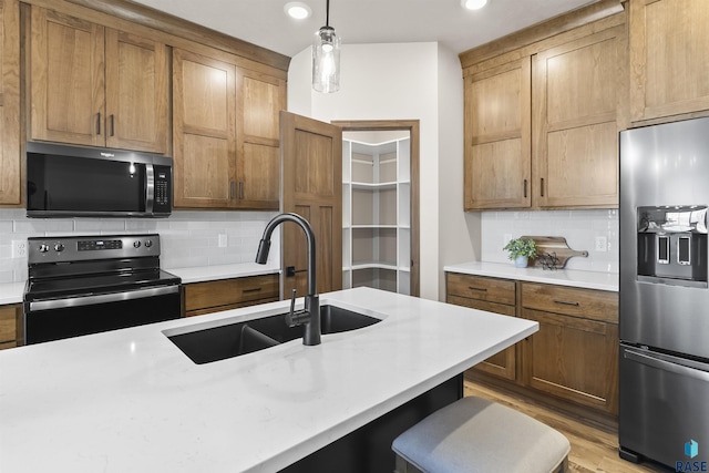 kitchen featuring light countertops, hanging light fixtures, a sink, range with electric cooktop, and stainless steel fridge