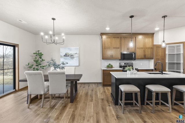 kitchen featuring tasteful backsplash, brown cabinets, stainless steel electric range, light countertops, and a sink